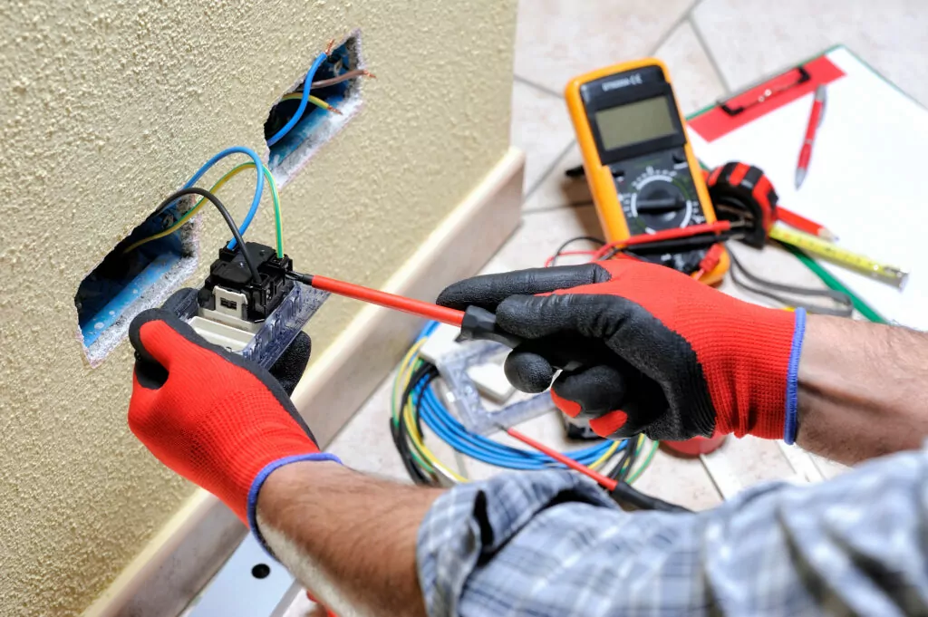 Un tecnico elettricista al lavoro con l'attrezzatura di sicurezza su un'asta