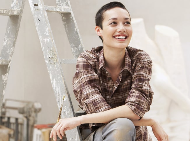 Una persona seduta su una scala dopo aver completato una task di pittura